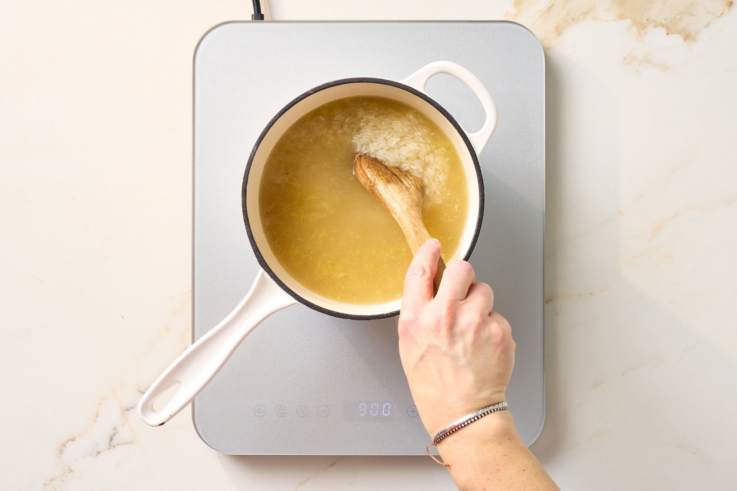 Person stirring rice in a pot on a stovetop