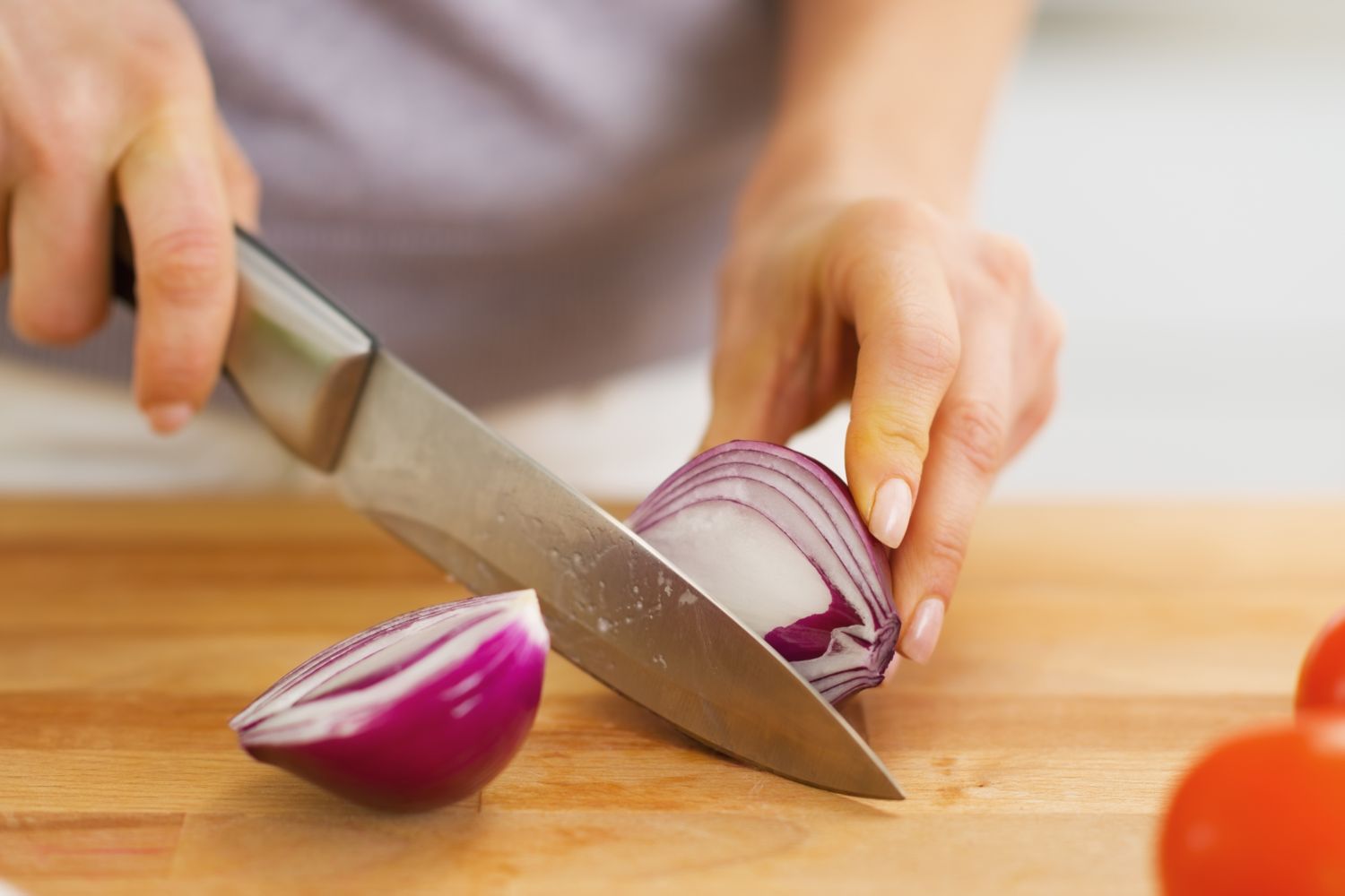 Closeup on woman cutting onion on cutting board