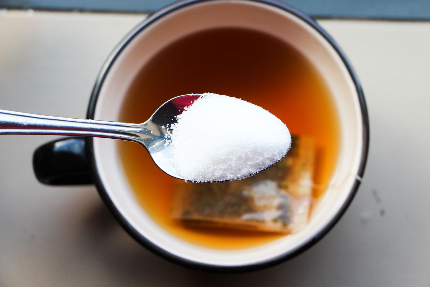 Sugar In Spoon Over Drink On Table
