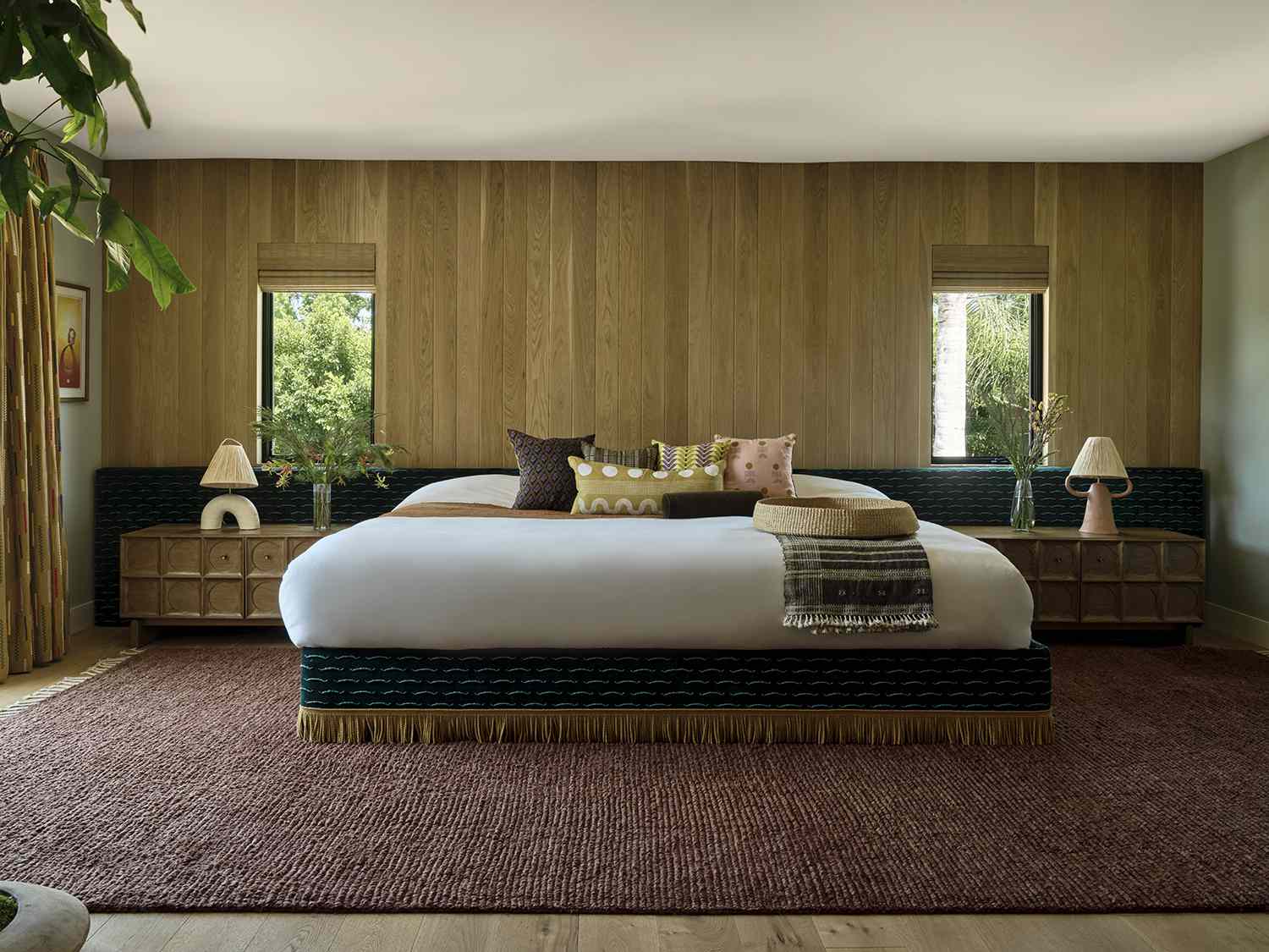 a king bed with a tasseled bed skirt and a textured, terracotta-colored rug underneath