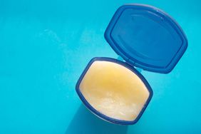 opened petroleum jelly jar on blue background