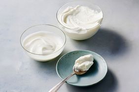 Two bowls of yogurt next to a spoon with yogurt on a small plate
