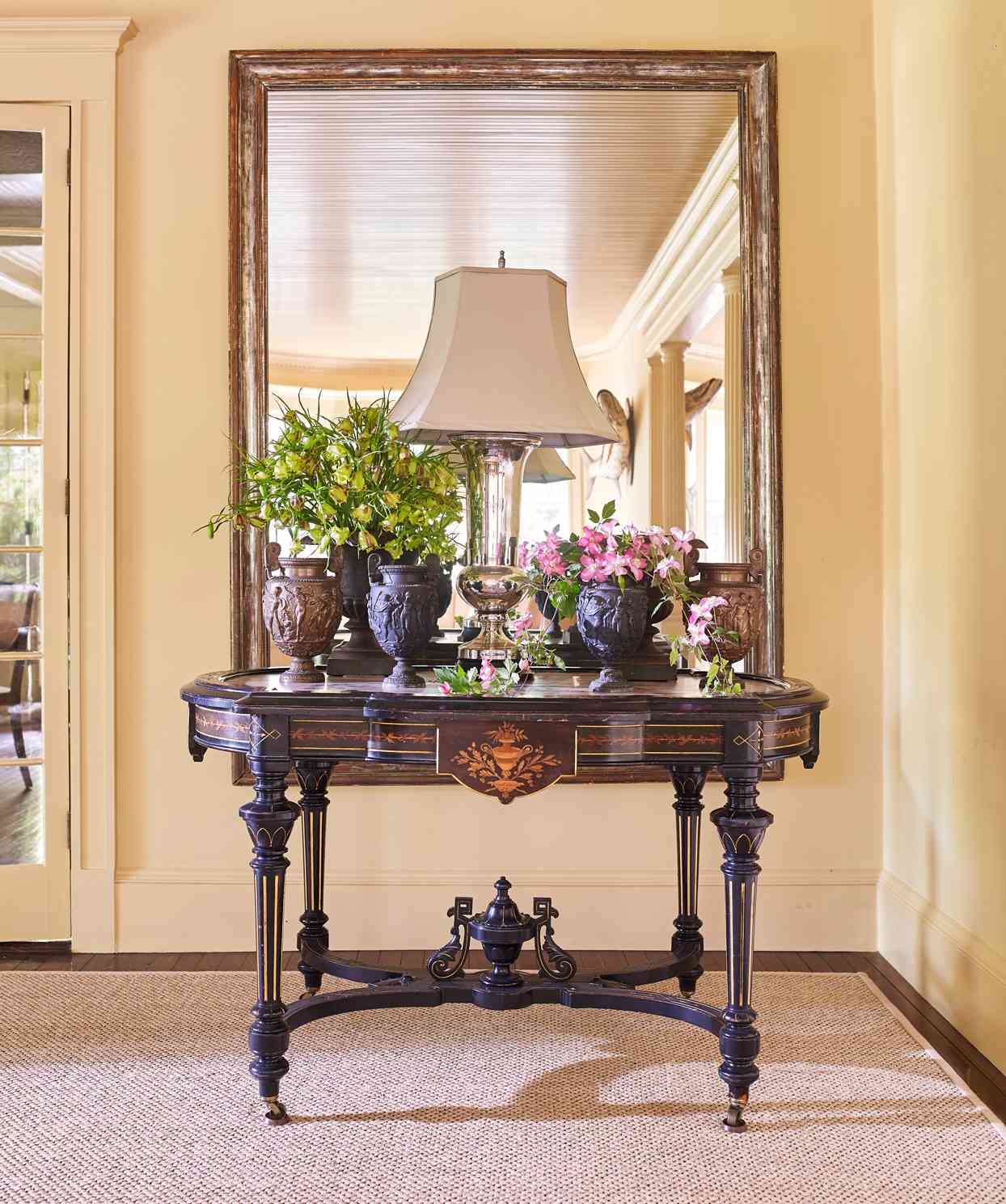 gilt-framed mirror hangs above aesthetic movement table with pink-marble top
