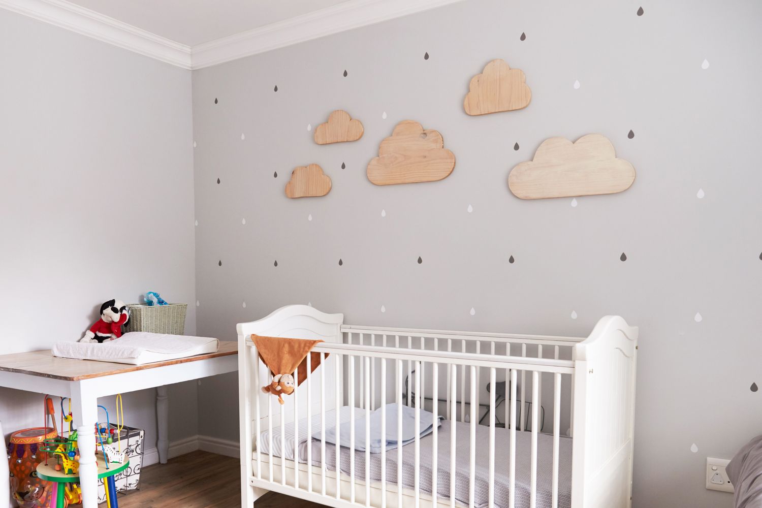 A nursery with a crib a changing table and cloudshaped wall decorations