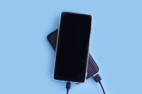 Smartphone and power bank on color background