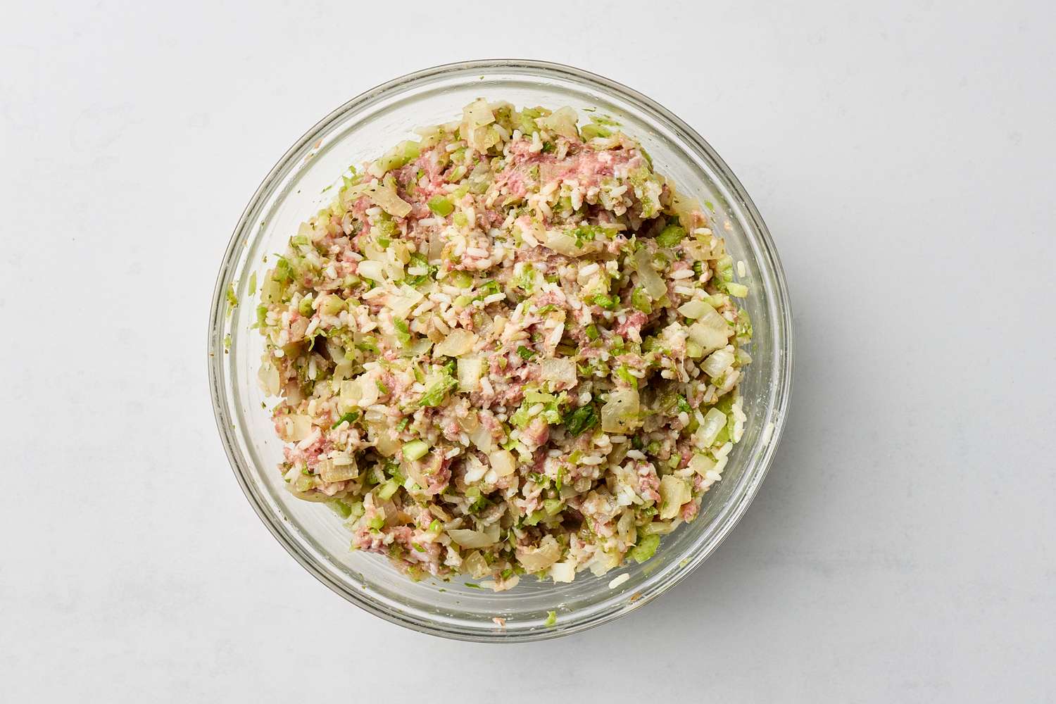 A glass bowl containing the prepared filling for stuffed cabbage finely mixed ingredients including meat and chopped vegetables