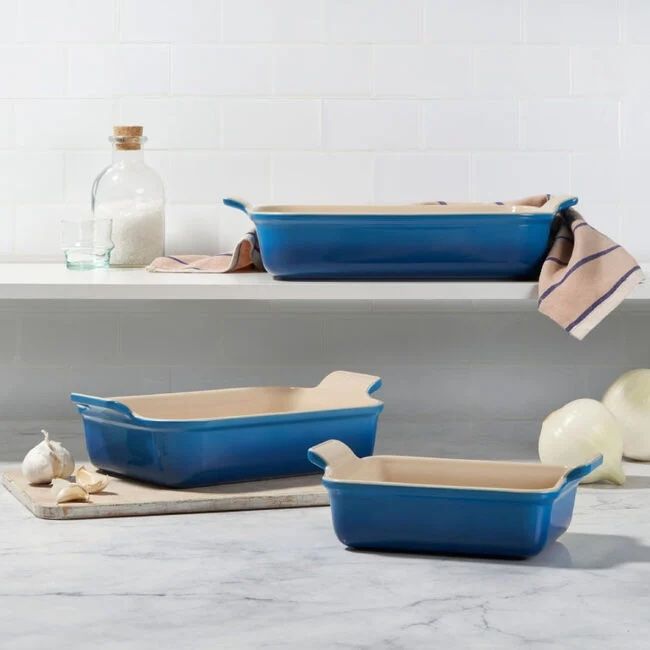 Three ceramic rectangular baking dishes in different sizes on a kitchen surface and shelf