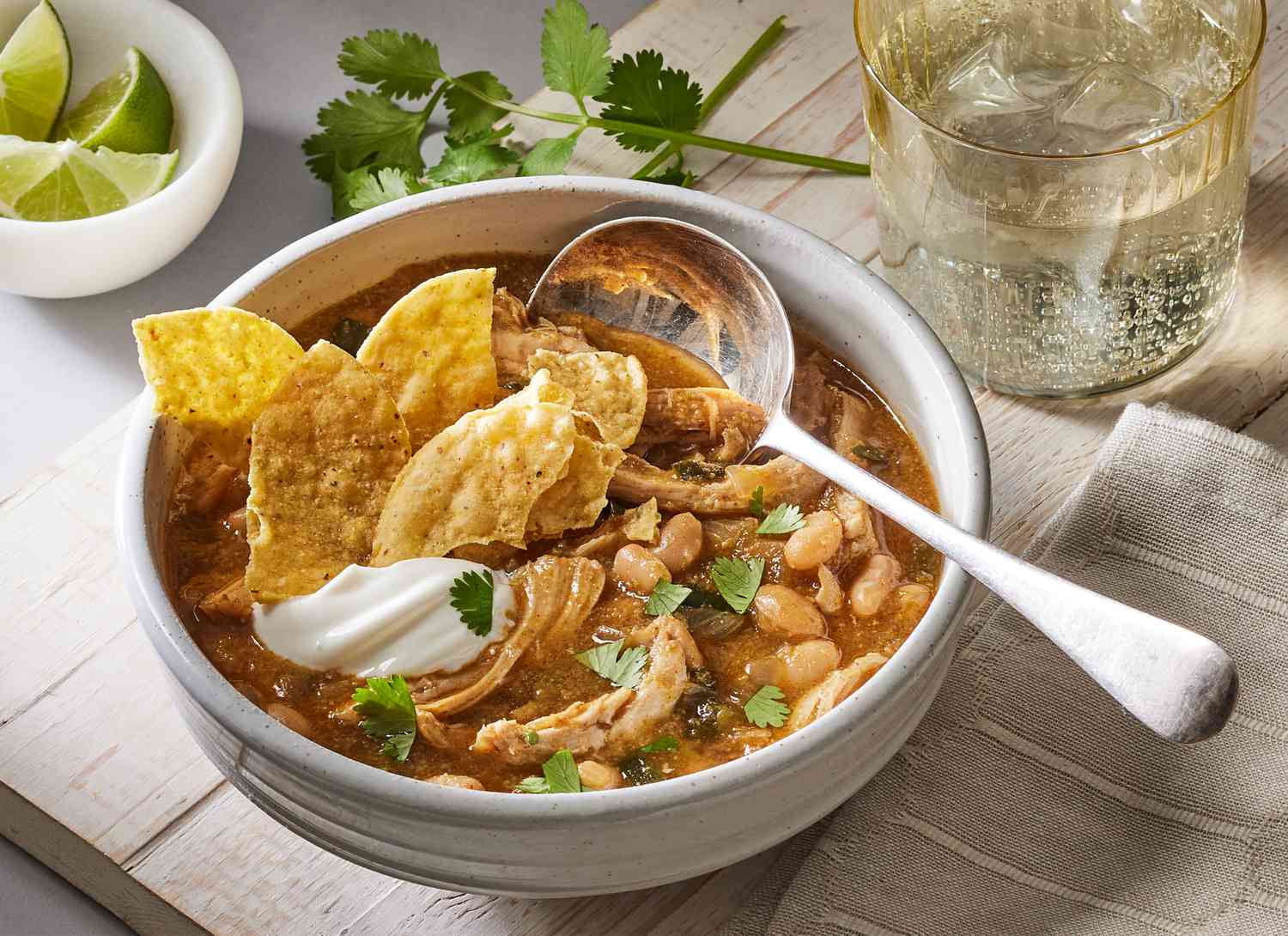 bowl of white bean chicken chili with spoon and tortilla chips, limes