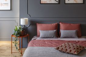 A bedroom setup with a bed adorned with pillows and a small side table decorated with plants and a lamp