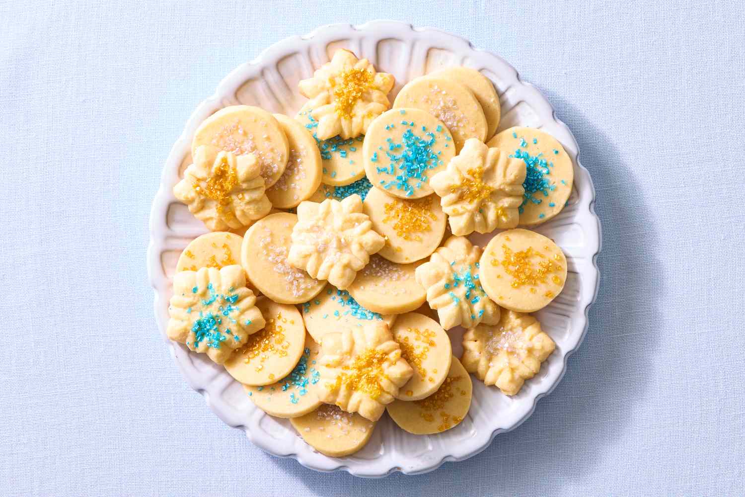 An assortment of butter cookies with decorative sprinkles on a white plate