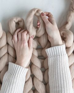 hands forming loops on top row of arm knit blanket