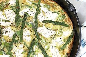 overhead view of a frittata with asparagus, goat cheese, and herbs