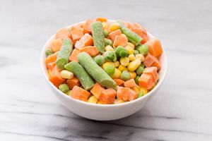 A bowl of mixed frozen vegetables including carrots green beans peas and corn