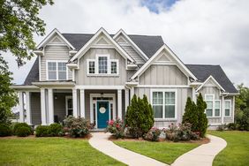 A large contemporary house with multiple gables and a front lawn with a pathway