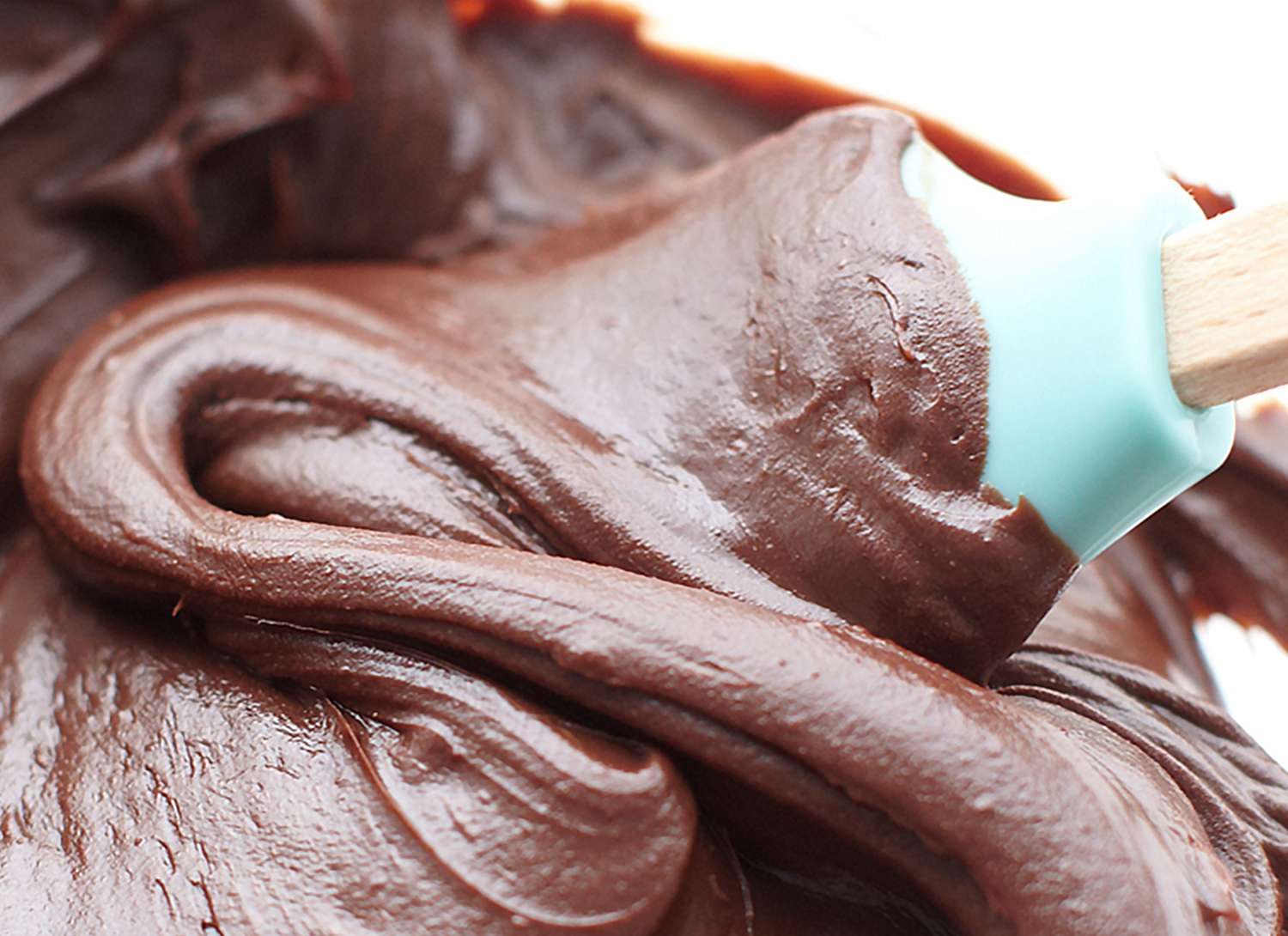 close up of chocolate frosting being stirred by a spatula