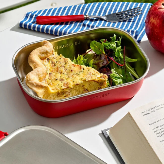 Lunch with quiche and salad in a red container on a picnic setup