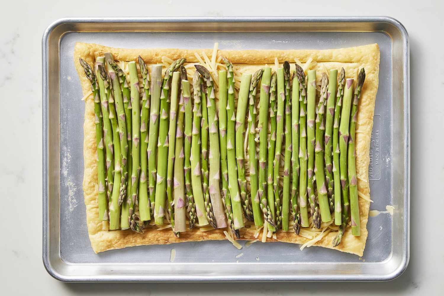 Asparagus and pastry dough on baking sheet