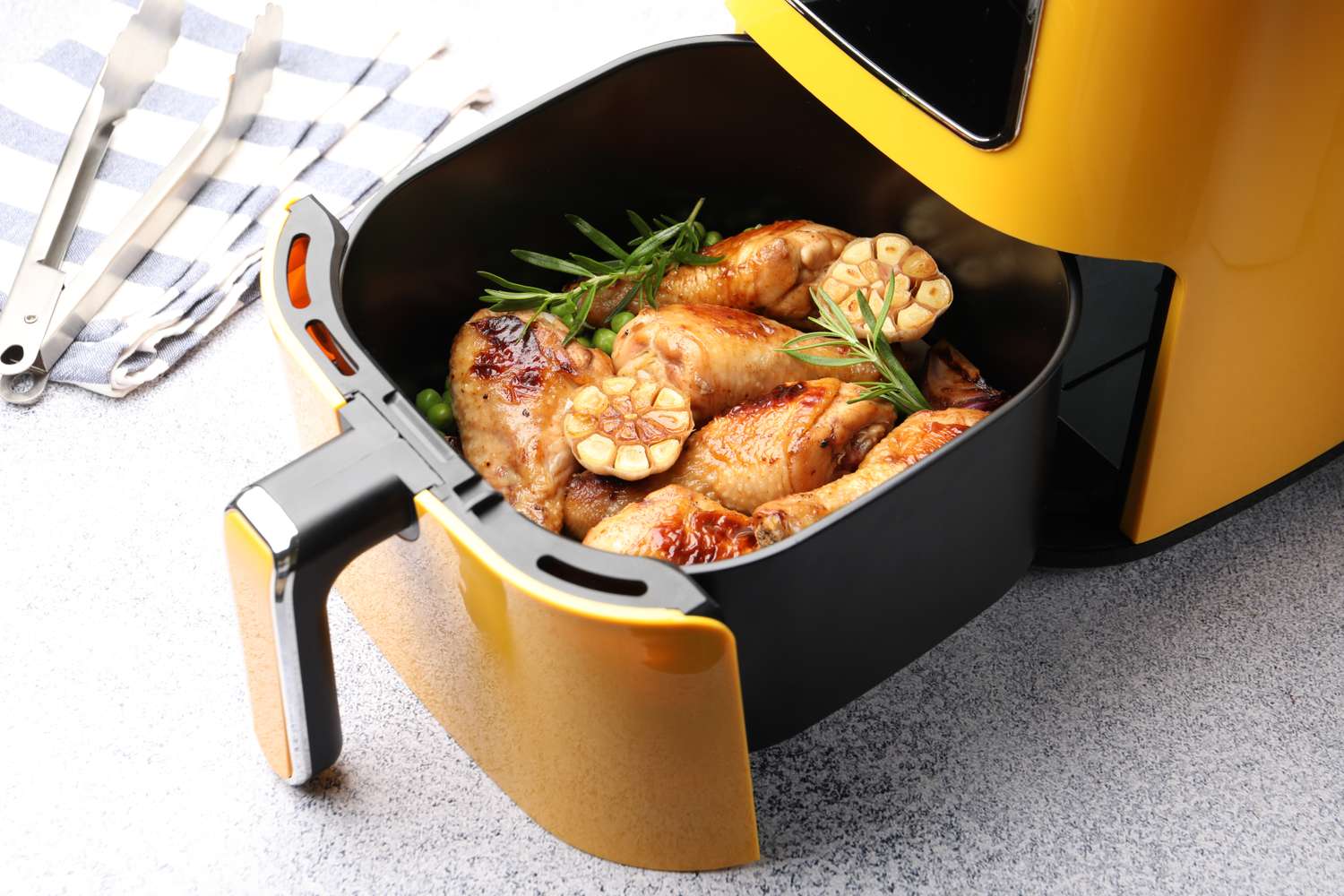 Cooked chicken drumsticks and garlic cloves in an air fryer basket