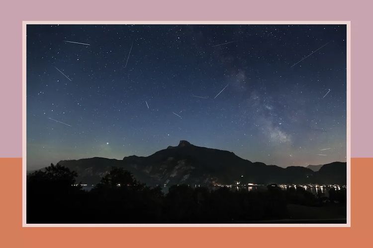 A mountain under a night sky with visible stars and meteor streaks hinting at a meteor shower