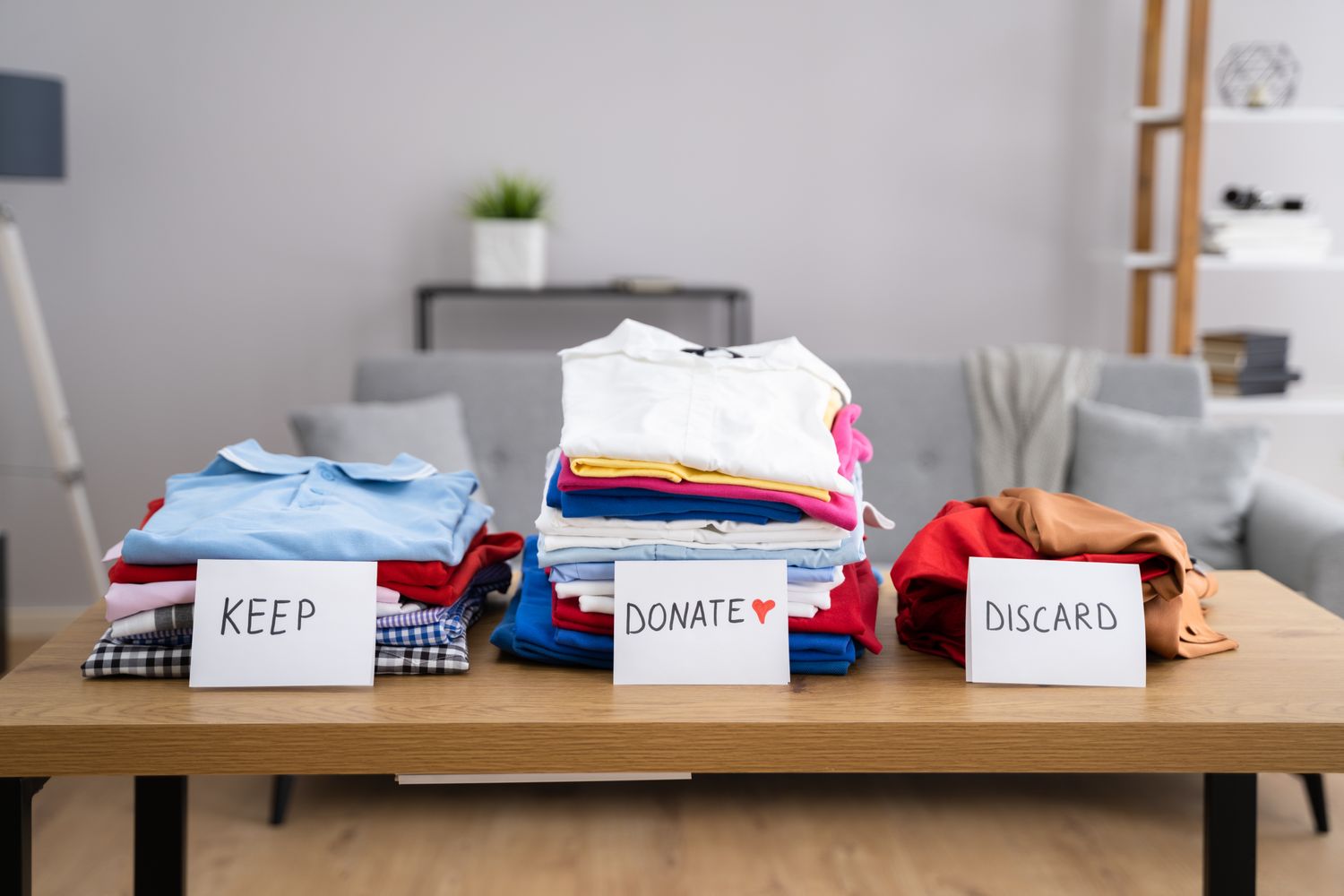 Three piles of folded clothes on a table labeled Keep Donate and Discard