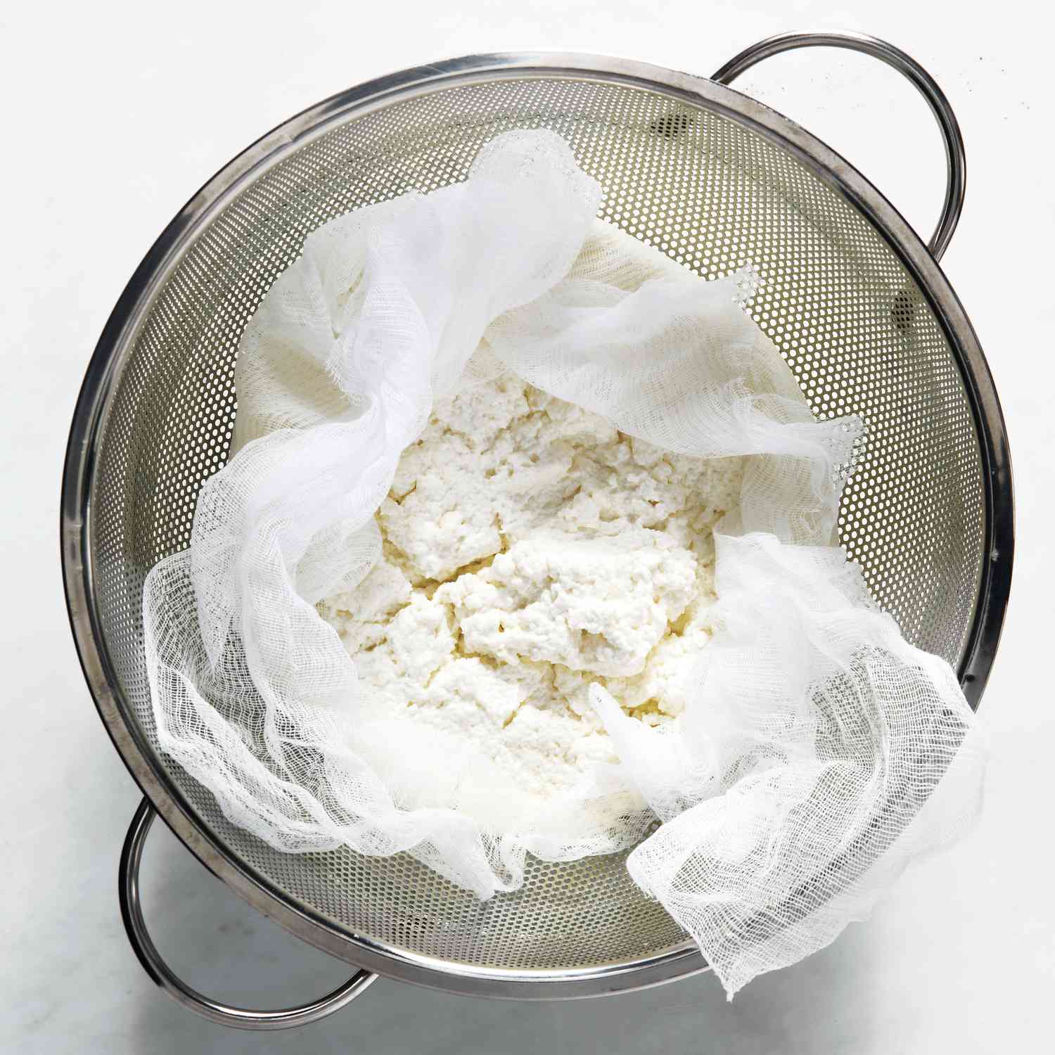 homemade ricotta draining in sieve
