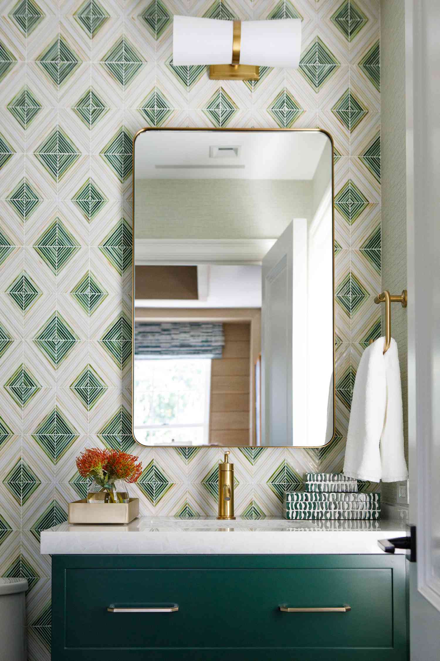 a diamond patterned tile wall sits behind brass fixtures