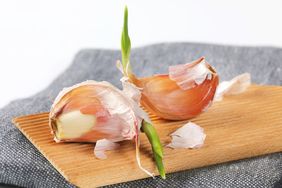 Two sprouted garlic cloves on a wooden surface