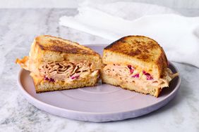 A sandwich with meat and slaw on toasted bread halves on a plate