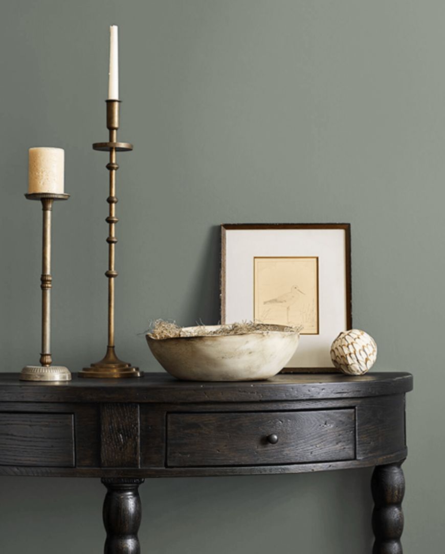 A table with decorative items including candlesticks a framed artwork and a bowl