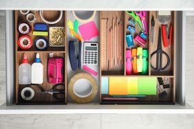 An organized drawer containing various office supplies including tape pens scissors highlighters and a calculator