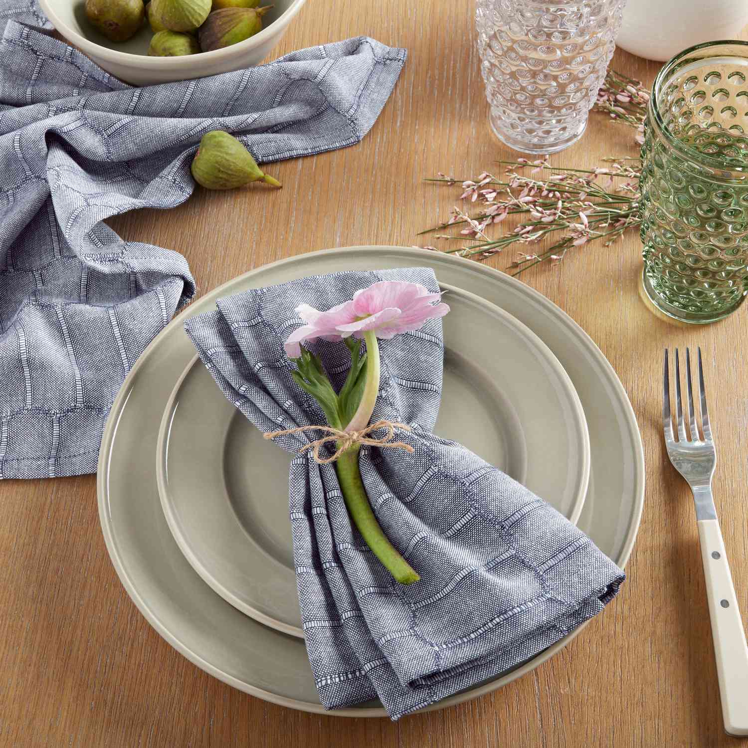 table place setting with napkin and flower on wood table