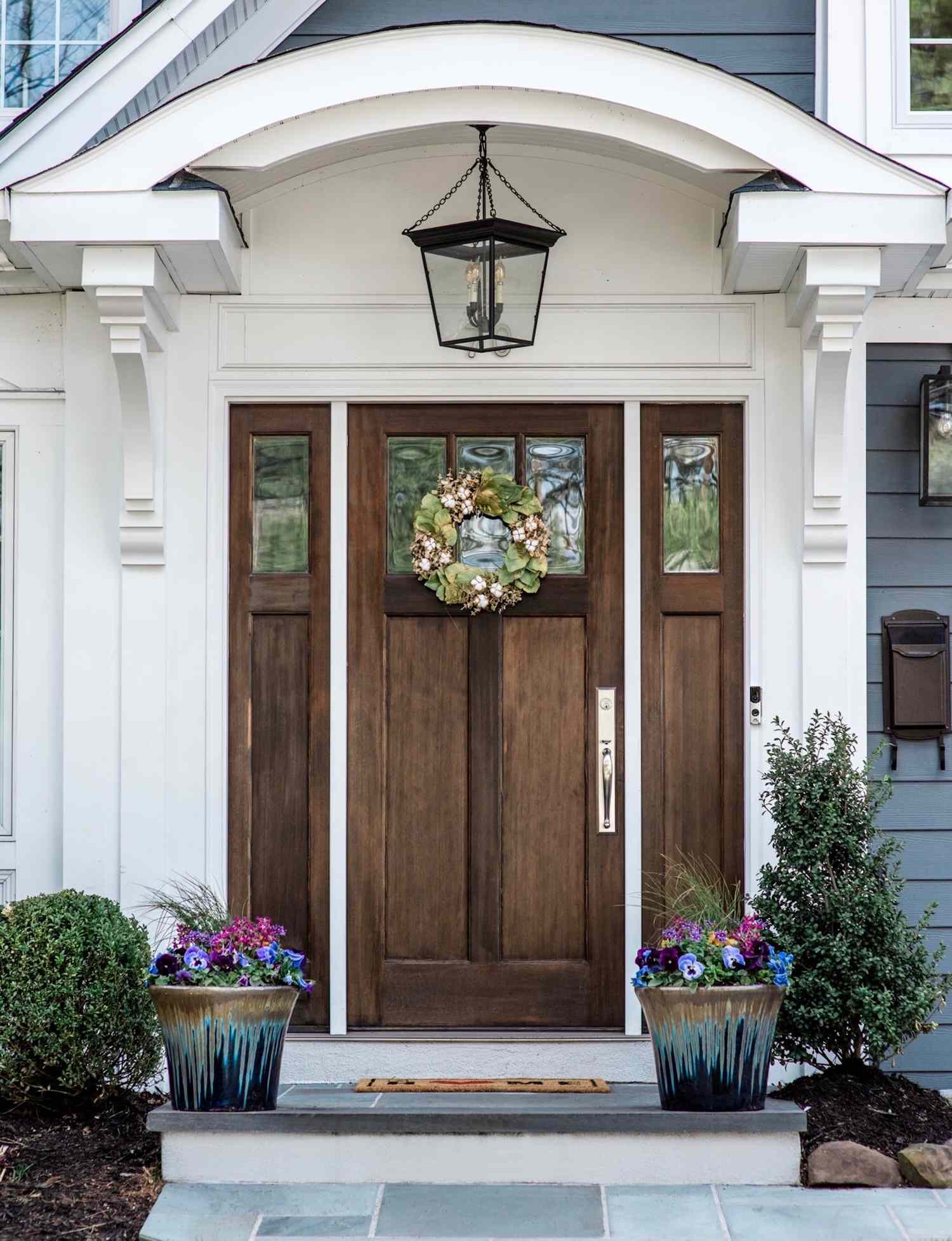 A front door with decorative plants and a floral wreath