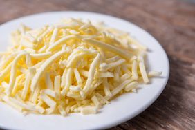 A plate of grated cheese on a wooden surface