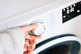 Hand turning a knob on a washing machine