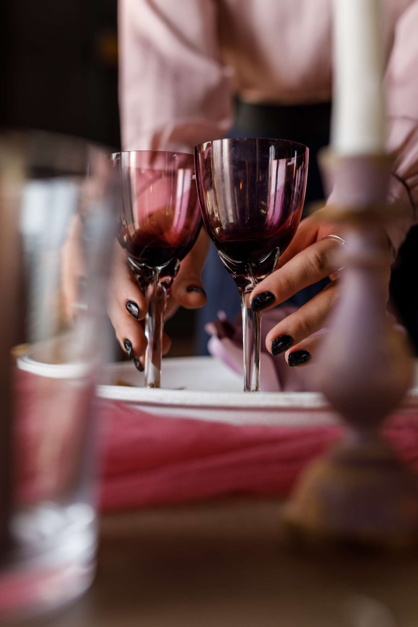Hands setting wine glasses on a table
