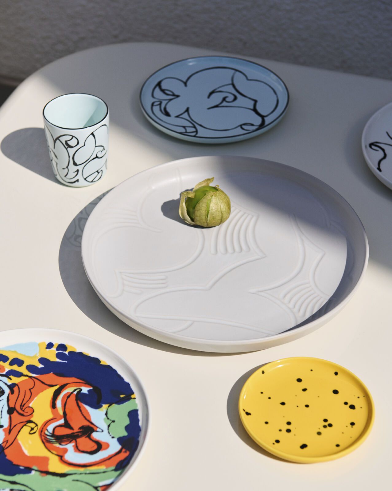 colorful ceramic dishes and mugs on a white table
