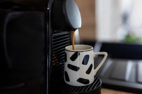 A coffee machine brewing coffee into a patterned mug