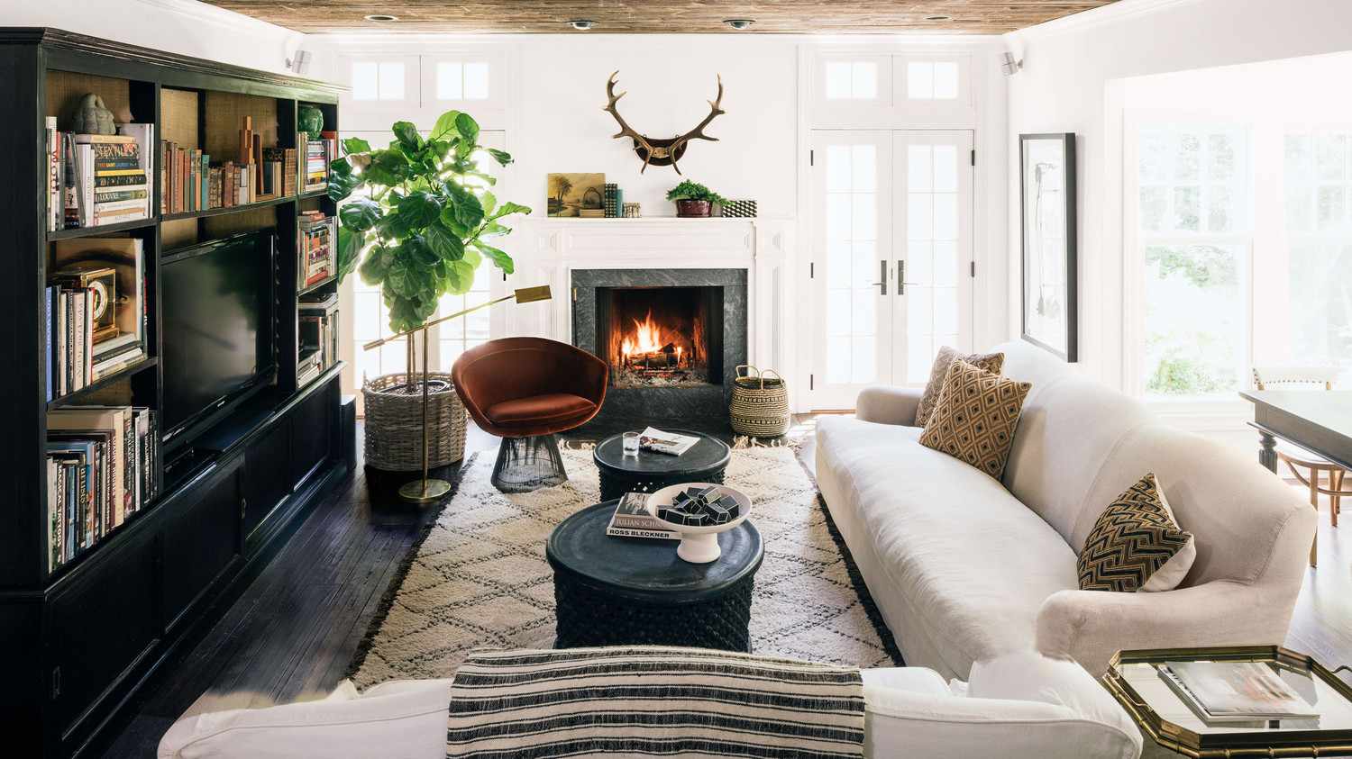 neutral family room with velvet chair and antlers hanging above fireplace