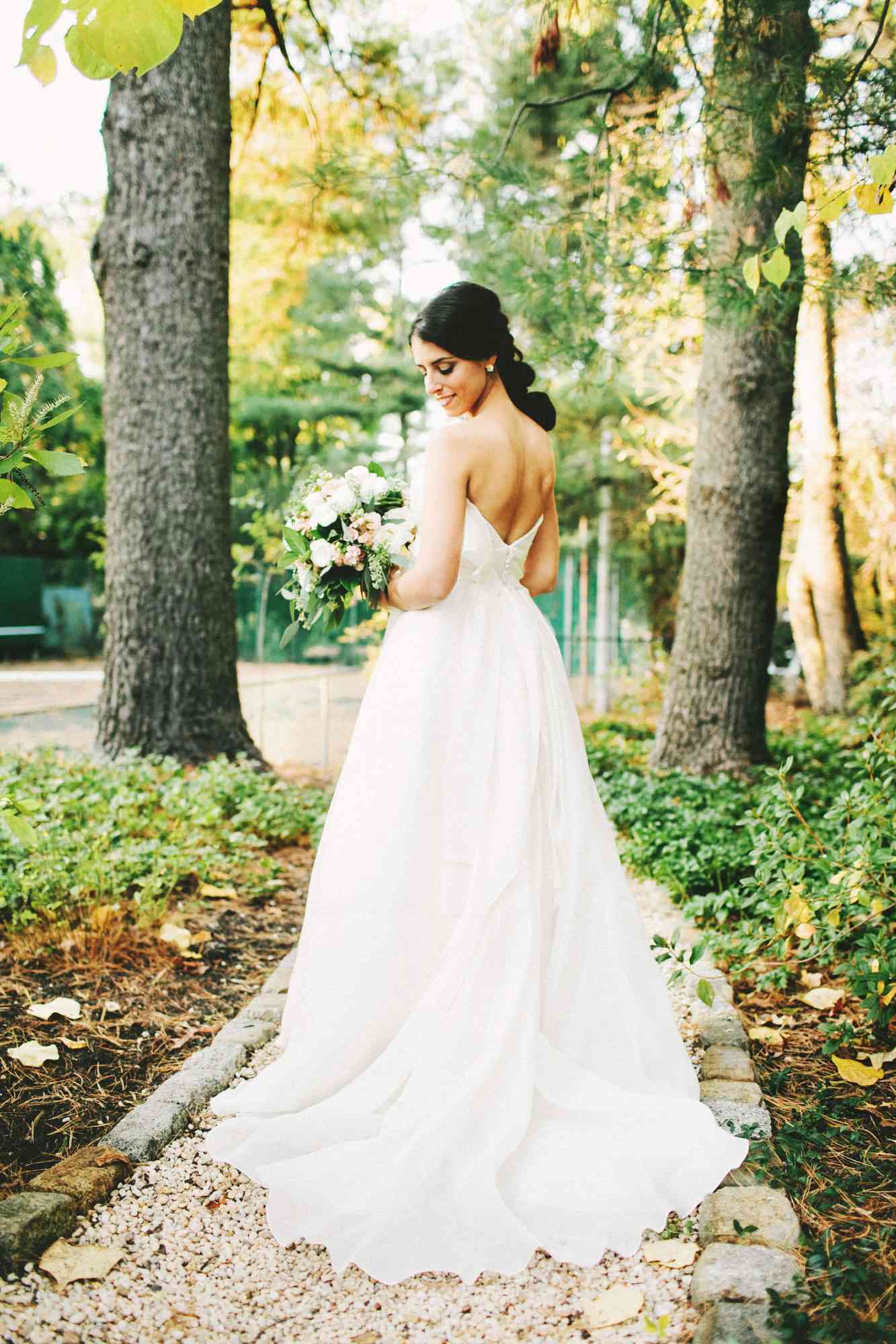 woman standing in garden in wedding dress- classic hair and makeup