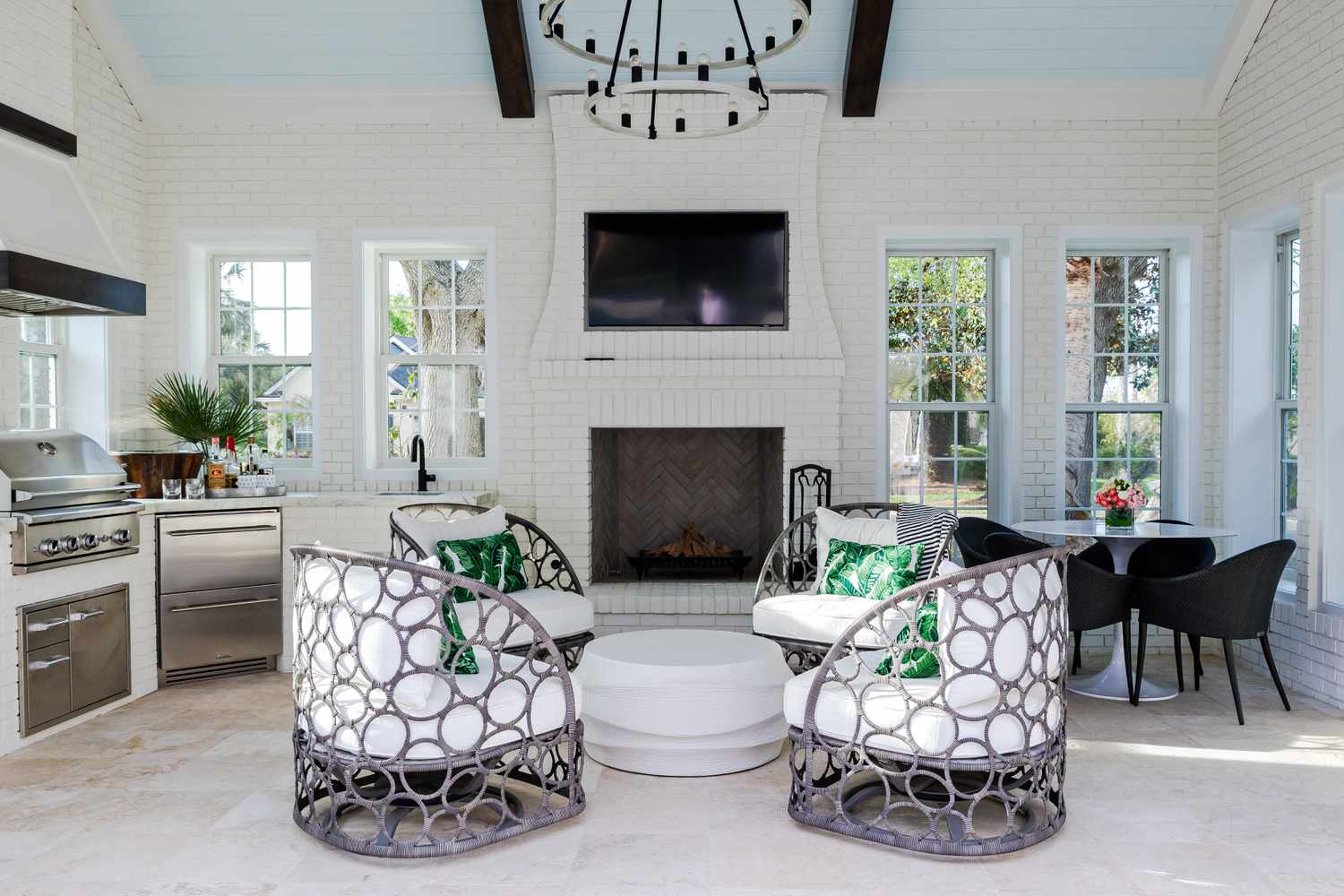 outdoor space under a pitched roof with circular seating, dining table, and a corner kitchen 