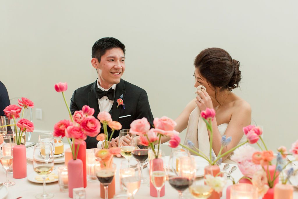 couple happy during wedding toasts at head table with flowers