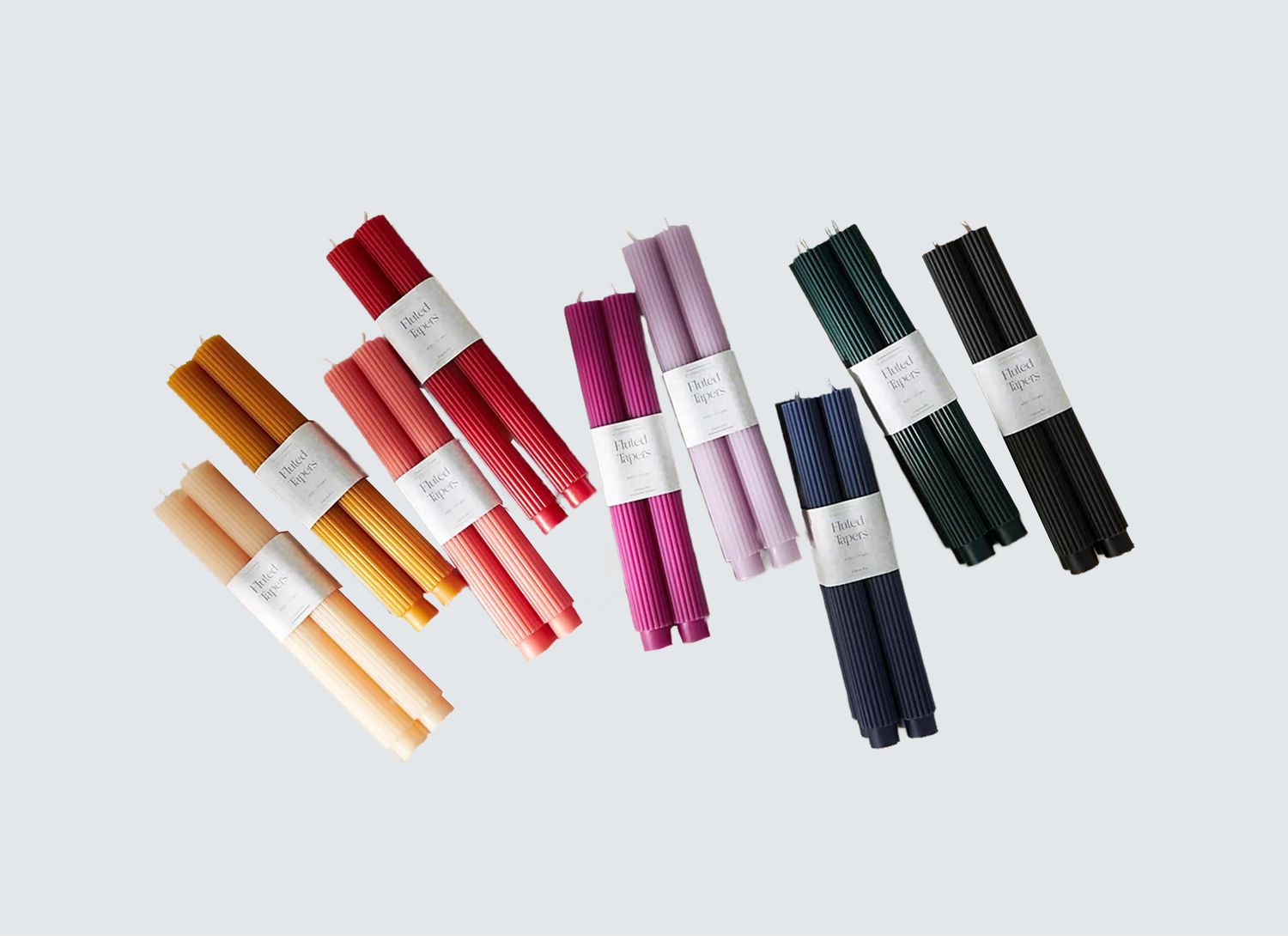 multiple colored, fluted tapered candles on a grey background