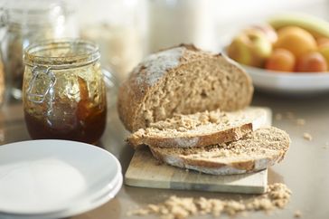 Sliced loaf of bread with a jar of preserves on a cutting board