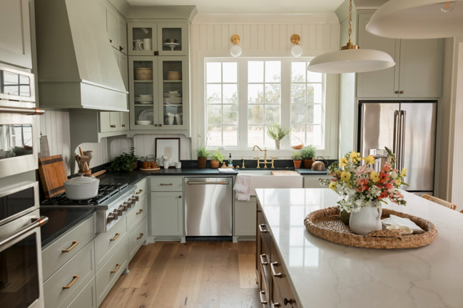 A modern kitchen with an island, stove, and sink by a window