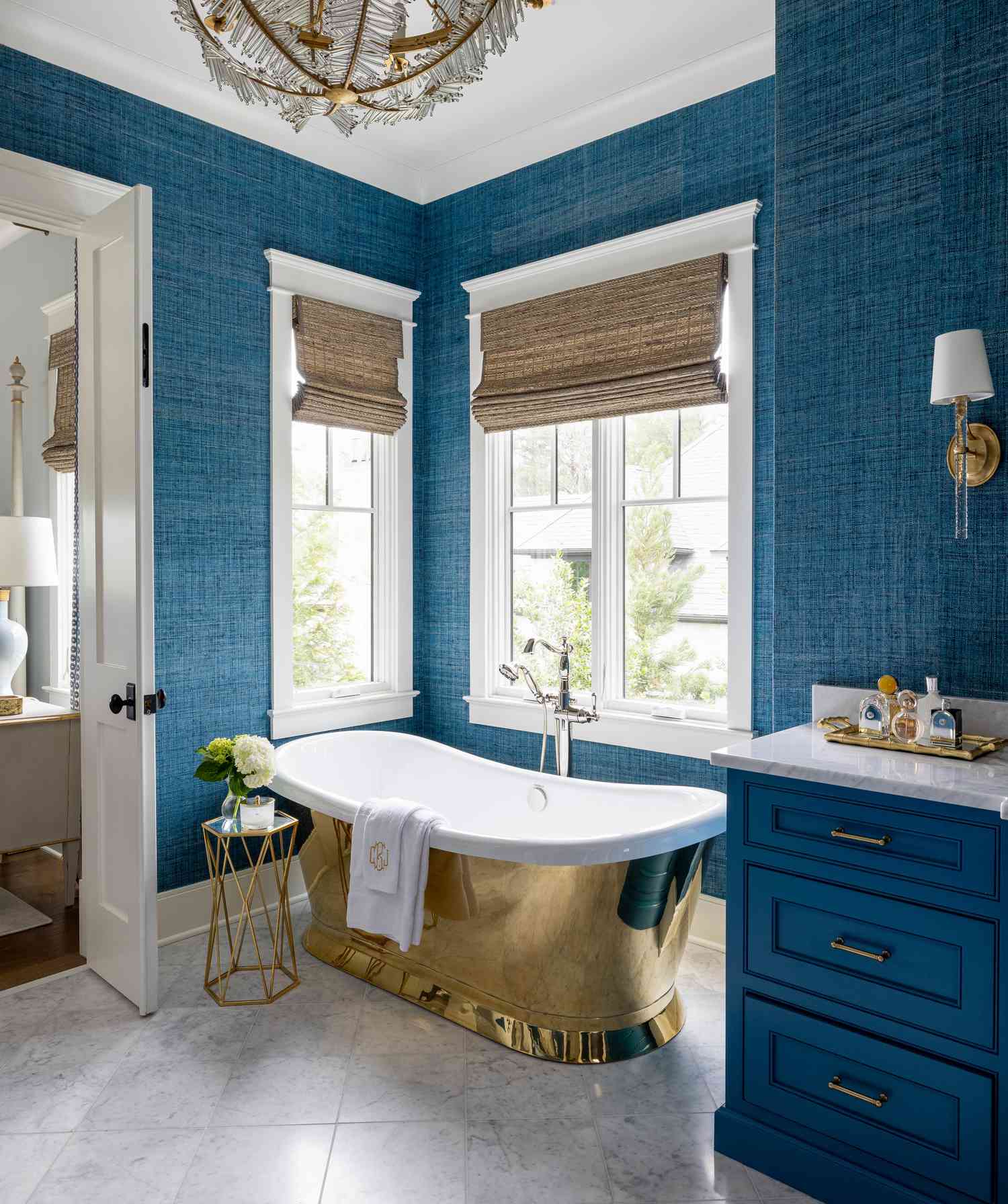 Luxurious bathroom with a freestanding tub, blue textured walls, and natural light from windows