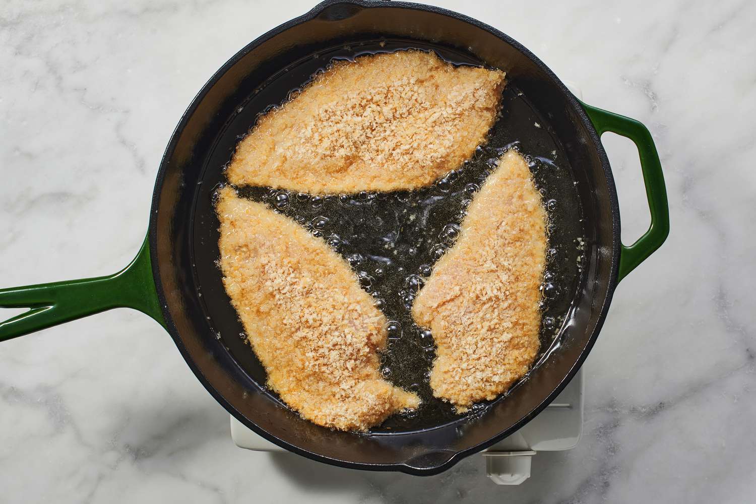 breaded chicken breasts cooking in skillet