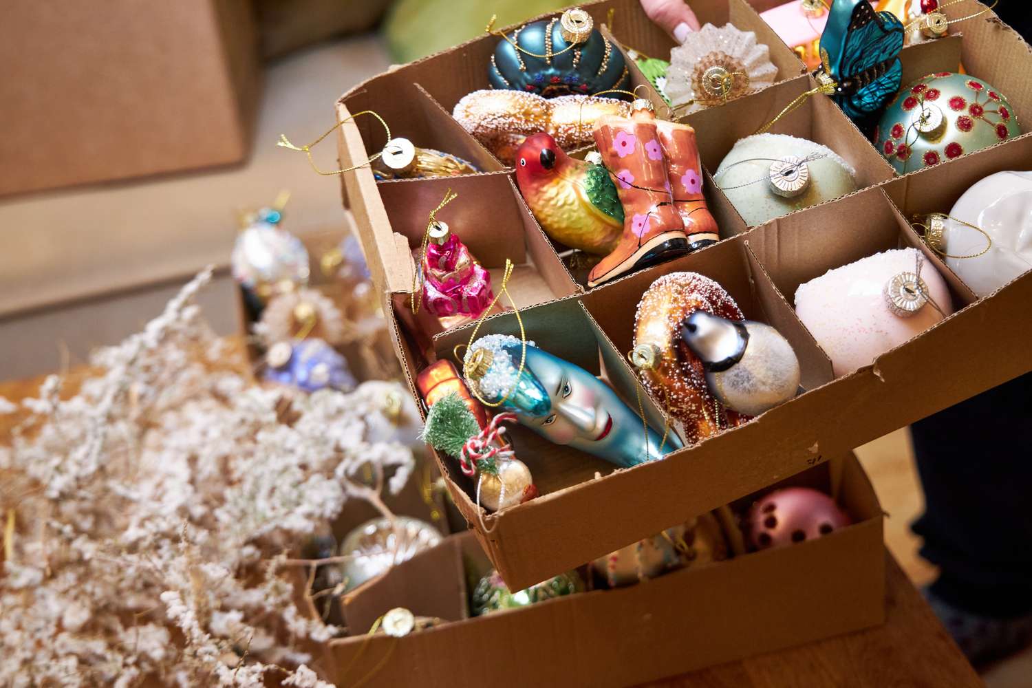 a woman holding a box of glass vintage Christmas tree toys