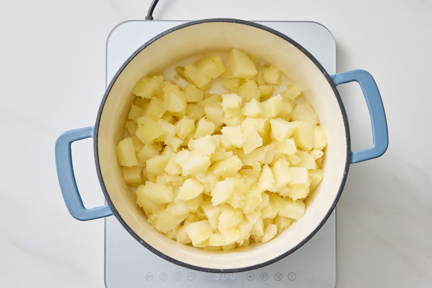 A pot on a stovetop filled with chopped cooked potatoes