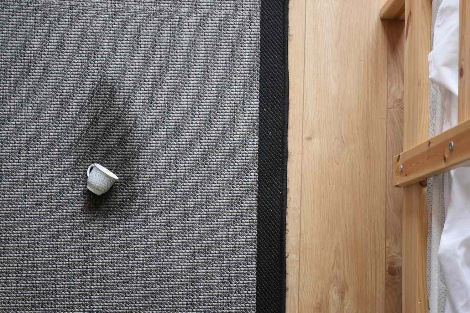 A small cup on a fabric rug next to a wooden surface