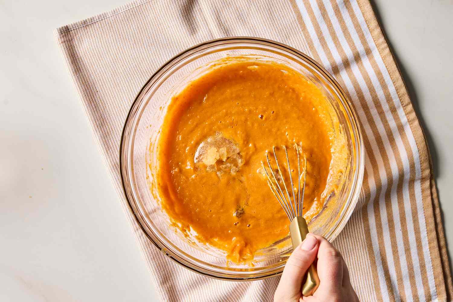 A glass bowl with pumpkin mousse mixture being whisked